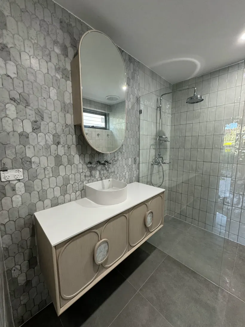 Hexagon tiled feature wall with an oval mirror above a fluted vanity
