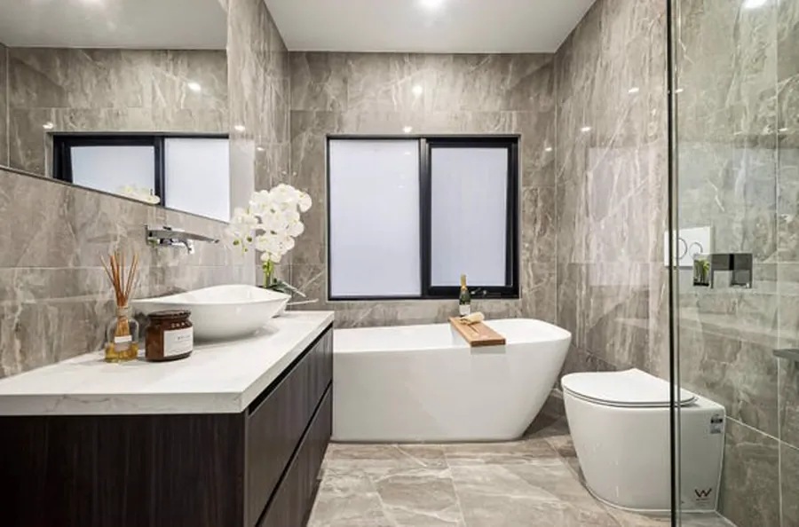 Stone tiled bathroom with a freestanding bath, timber vanity and wall-hung toilet